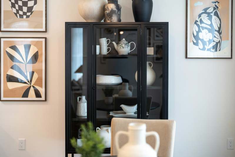 A clean, well-lit workspace with open display cases, styled with books, small sculptures, and framed prints